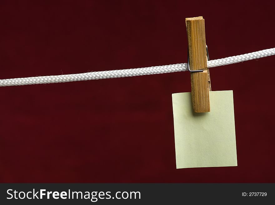 Yellow paper attach clothes-peg to rope on vinous background