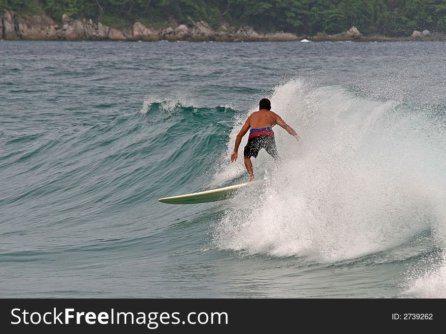 A local surfer rides a wave in Phuket, Thailand. A local surfer rides a wave in Phuket, Thailand