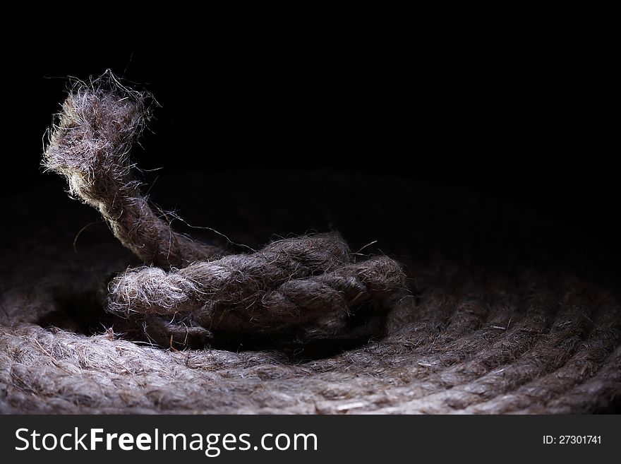 Skein of old hemp rope on dark background with free space for text