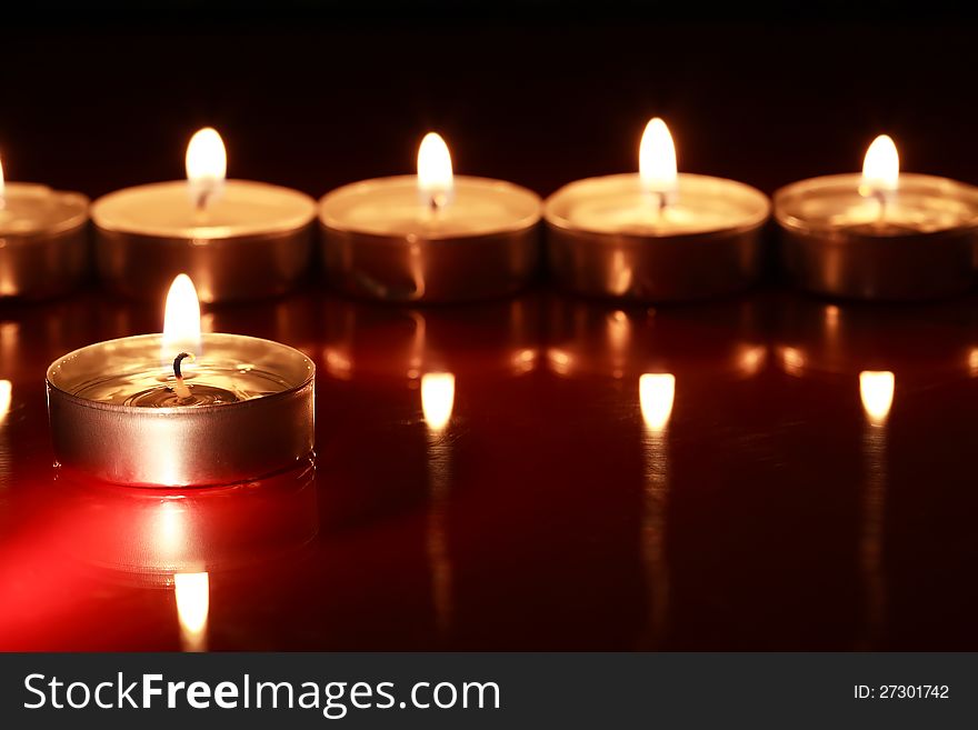 Set of lighting candles in a row on dark background with reflection. Set of lighting candles in a row on dark background with reflection