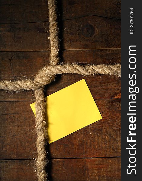 Blank yellow paper attached to wooden surface with rope. Blank yellow paper attached to wooden surface with rope