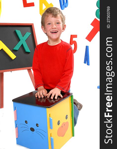 Happy young boy in preschool on isolated white background with bright letters and numbers. Happy young boy in preschool on isolated white background with bright letters and numbers