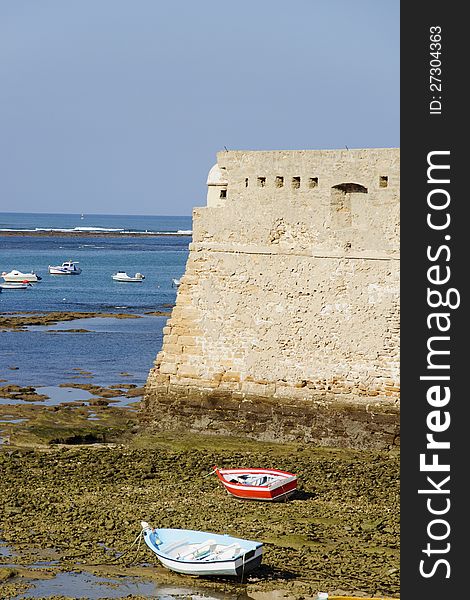 Boats lie on the rocks on low tide in the bay of Cadiz