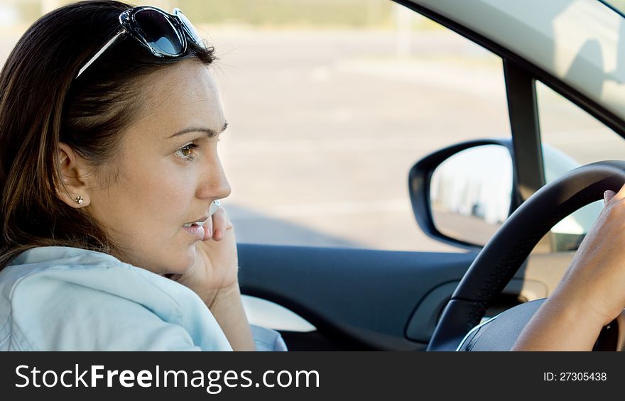 Closeup of an attractive trendy woman sittting behind the steering wheel of a car. Closeup of an attractive trendy woman sittting behind the steering wheel of a car