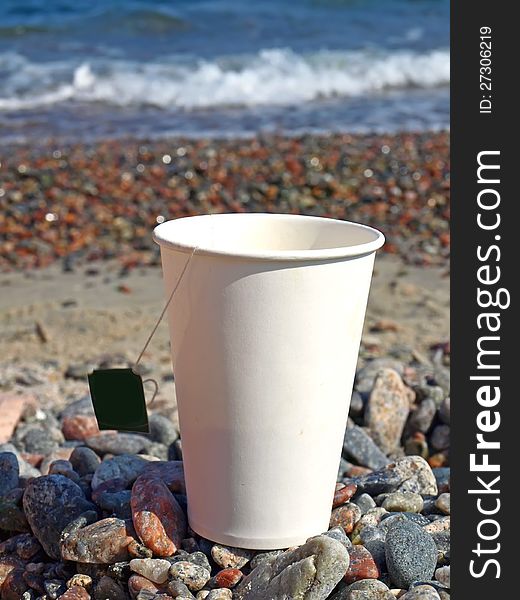 Paper cup on the pebbles on the sea background