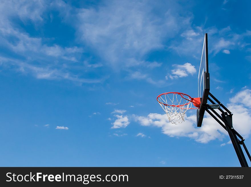 A basketball hoop and backboard against a cloudy background. A basketball hoop and backboard against a cloudy background
