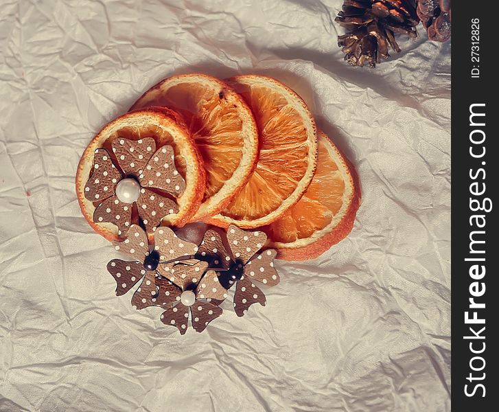 On a white table are dried orange segments and paper flowers. On a white table are dried orange segments and paper flowers