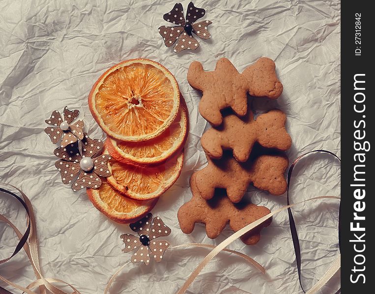 On a white table are dried orange segments and Christmas cookies. On a white table are dried orange segments and Christmas cookies