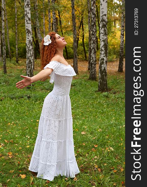 Beautiful red-haired young woman, wearing in white dress or the bride and decoration in form of flower on her head looking up, arms. as if flying. The concept of happiness and freedom. Beautiful red-haired young woman, wearing in white dress or the bride and decoration in form of flower on her head looking up, arms. as if flying. The concept of happiness and freedom.