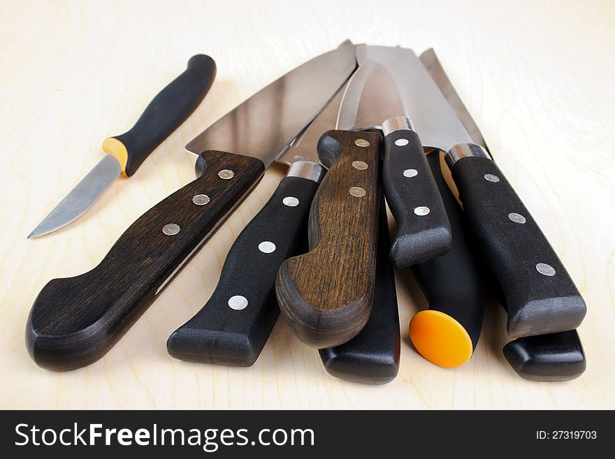 Stack of kitchen knives, wooden background. Stack of kitchen knives, wooden background