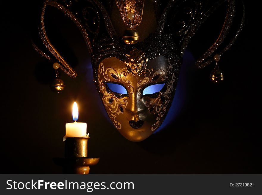Lighting candle against beautiful classical venetian mask on dark background. Lighting candle against beautiful classical venetian mask on dark background