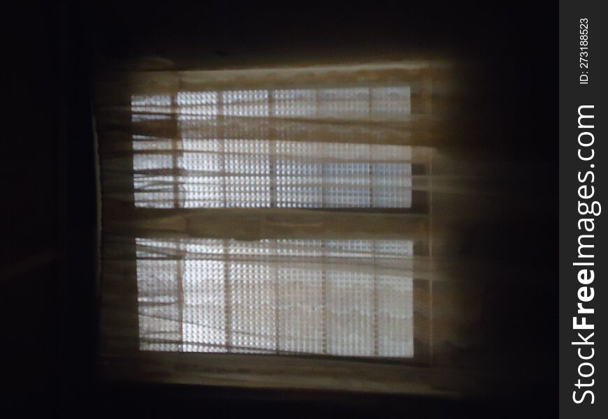 silhouette of a window with blinds in a dark room