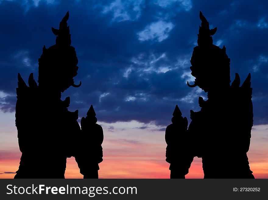 Silhouette by two giant statues standing tall on the background of a beautiful sky. Silhouette by two giant statues standing tall on the background of a beautiful sky.