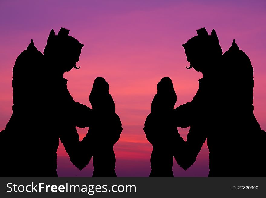 Silhouette by two giant statues standing tall on the background of a beautiful sky. Silhouette by two giant statues standing tall on the background of a beautiful sky.