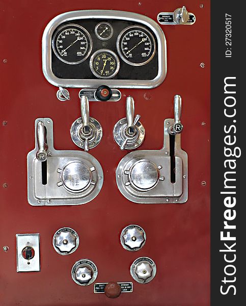 Close-up of the water valve control panel on the side of a vintage red fire truck. Close-up of the water valve control panel on the side of a vintage red fire truck.