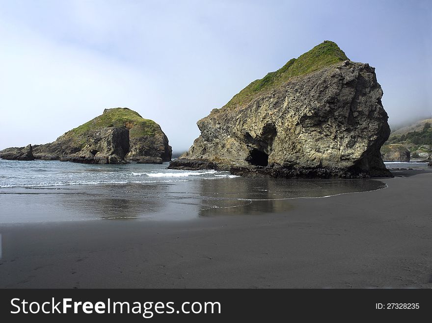 Sea stacks loom on the US west coast as the tide rolls in.