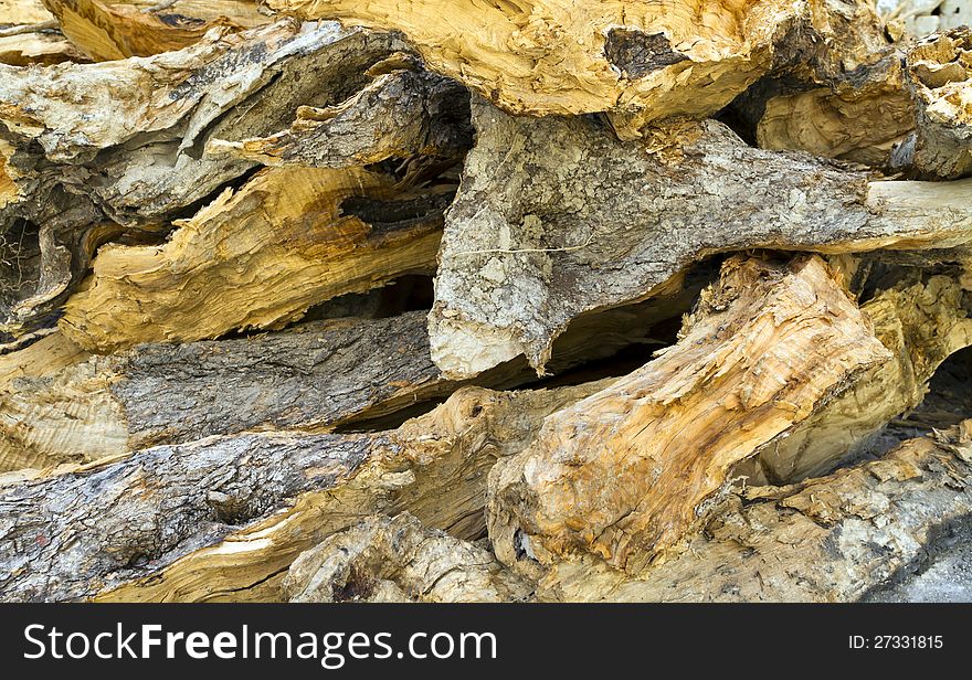 Background of dry roughly chopped firewood stacked up on top of each other in a pile