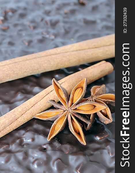 A close-up of cinnamon sticks and anise stars on top of chocolate cake
