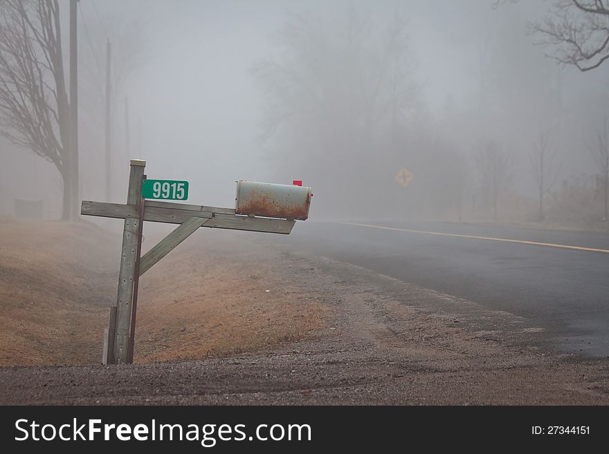 A mailbox on a country road in the fog. A mailbox on a country road in the fog