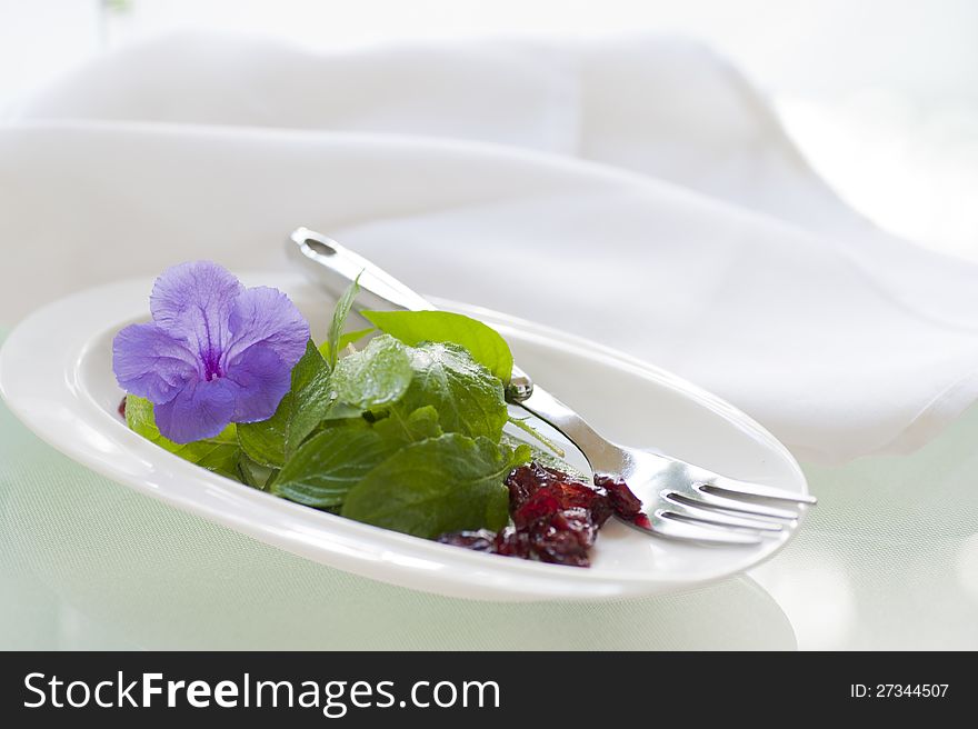 Delicious light salad of fresh greens and dried canberries garnished with an edible flower.