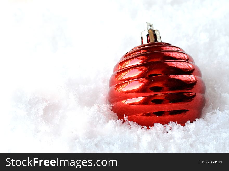 Shiny red Christmas tree decoration in soft snow. Copy space. Shiny red Christmas tree decoration in soft snow. Copy space.