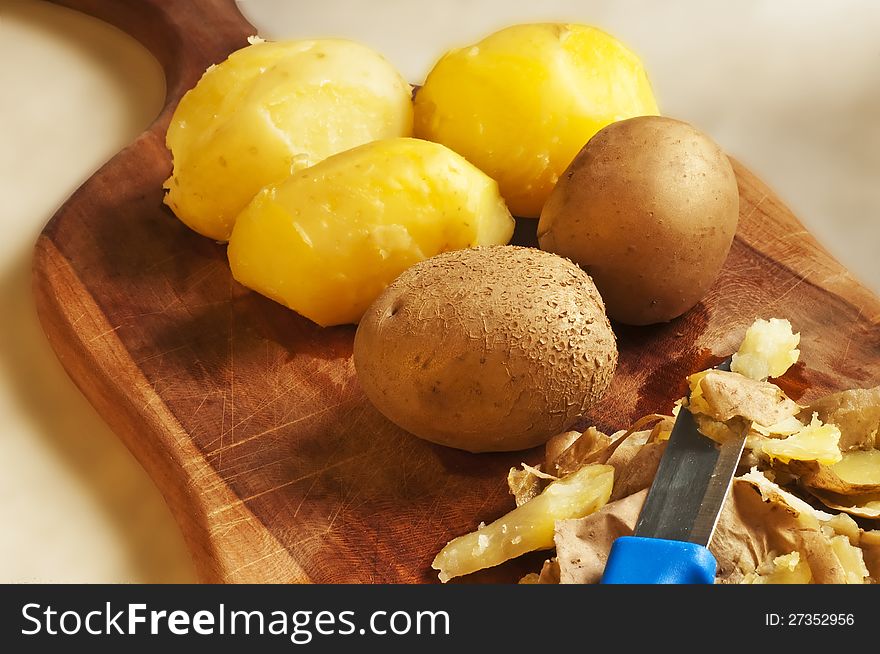 Peeled potatoes on a board wit a knife. Peeled potatoes on a board wit a knife