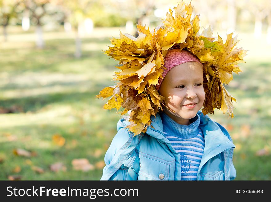 Small girl in a crown of autumn leaves