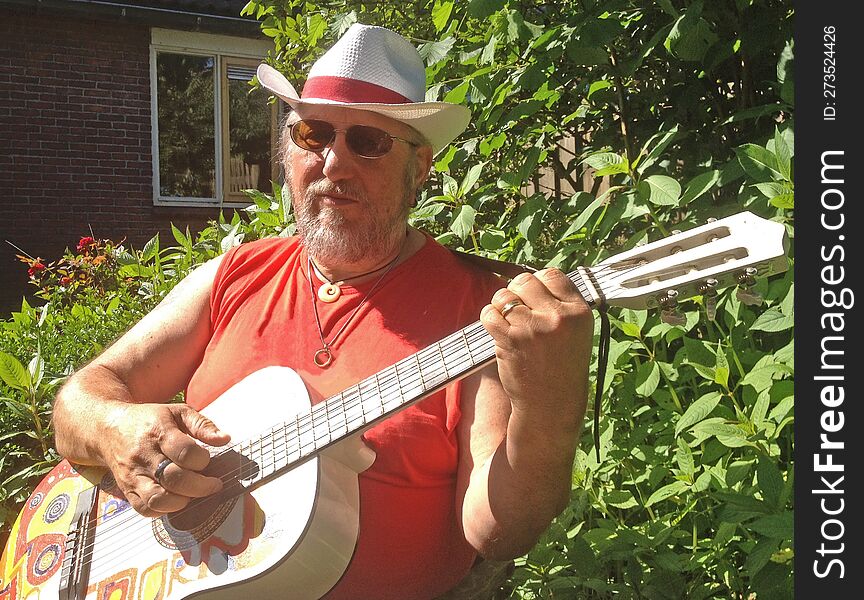 An elderly man plays the guitar