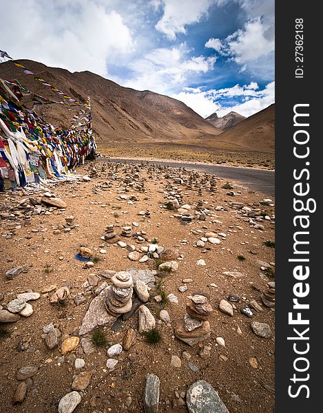 Highland road pass with stone pyramid and Buddhist praying flags. India, Ladakh, Leh-Chumathang-Tso Moriri highway, altitude 4500 m. Highland road pass with stone pyramid and Buddhist praying flags. India, Ladakh, Leh-Chumathang-Tso Moriri highway, altitude 4500 m