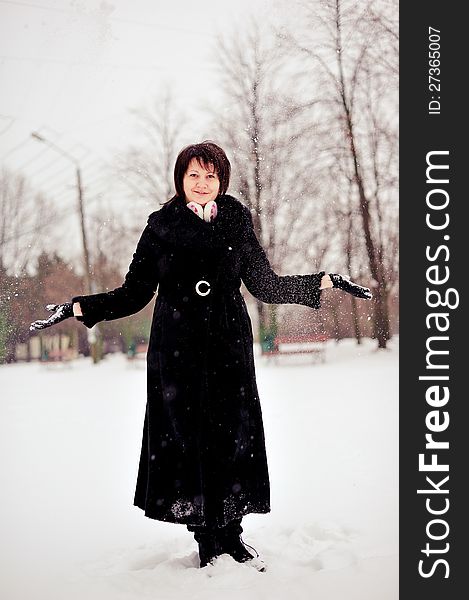 Outdoors in winter woman in a black fur coat playing with snow. Outdoors in winter woman in a black fur coat playing with snow