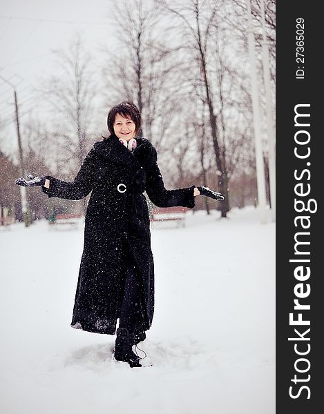 Outdoors in winter woman in a black fur coat playing with snow. Outdoors in winter woman in a black fur coat playing with snow