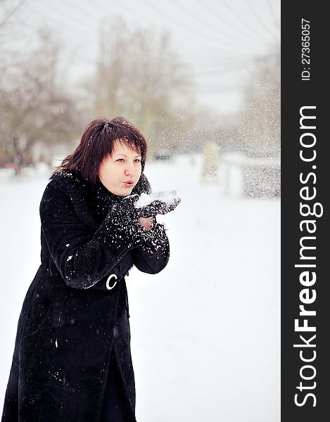 Outdoors in winter woman in a black fur coat playing with snow. Outdoors in winter woman in a black fur coat playing with snow