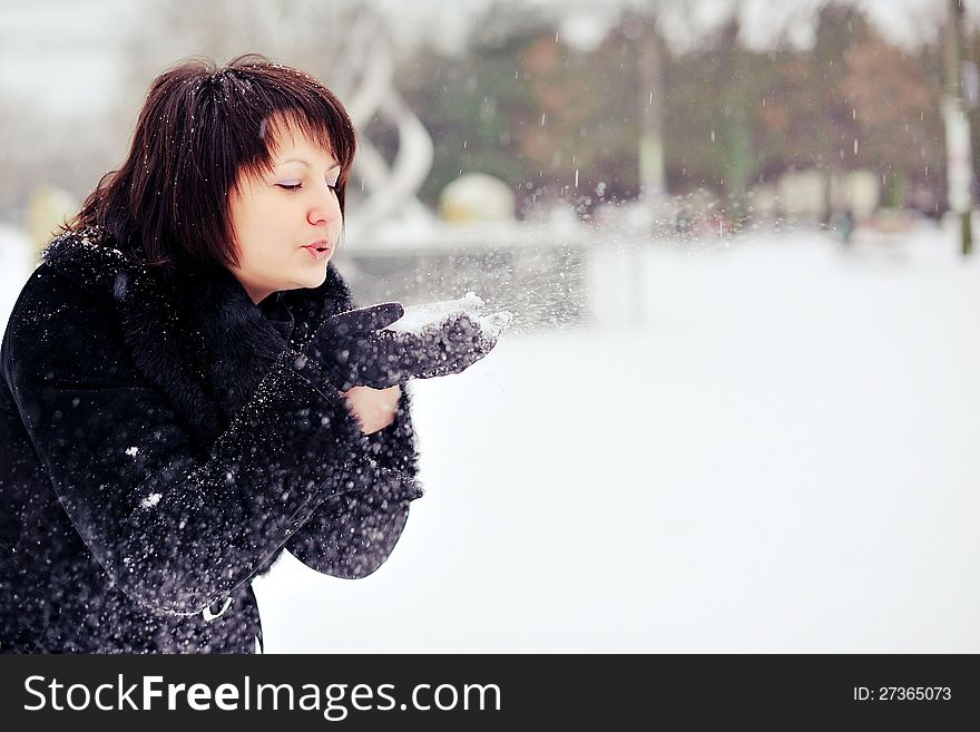 Outdoors in winter woman in a black fur coat playing with snow. Outdoors in winter woman in a black fur coat playing with snow