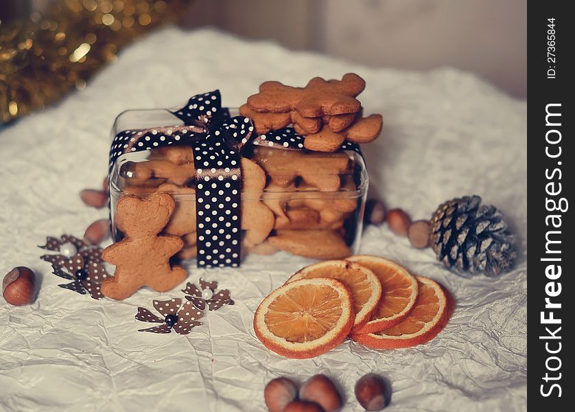 On a white table are dried orange segments and a box of biscuits, nuts and cones. On a white table are dried orange segments and a box of biscuits, nuts and cones