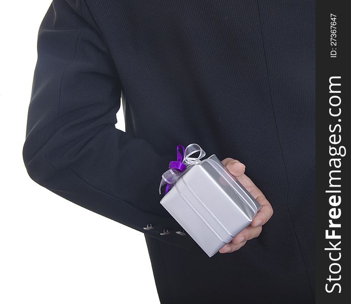 Man in a black suit hiding a present behind his back isolated on white background. Man in a black suit hiding a present behind his back isolated on white background