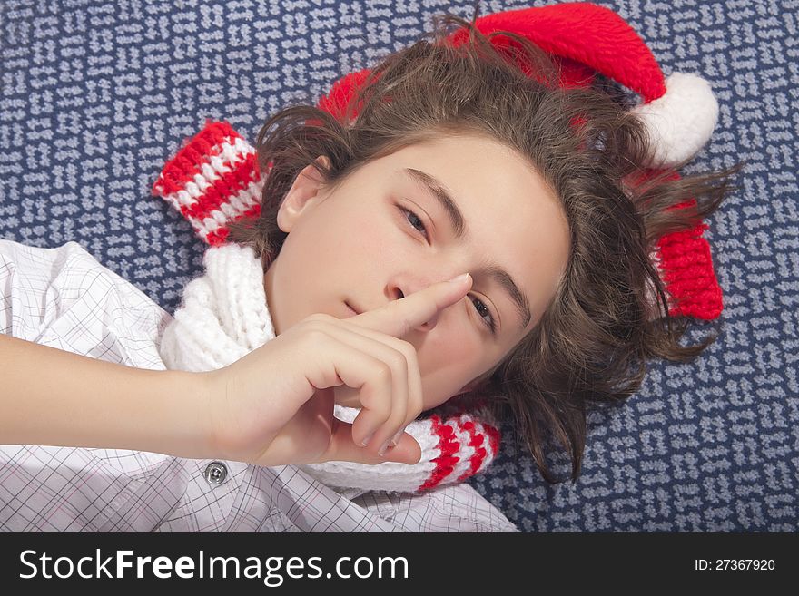 Sleepy handsome teenage boy lying on the floor with Christmas hat. Sleepy handsome teenage boy lying on the floor with Christmas hat