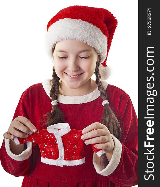 Beautiful girl dressed in Christmas clothes and red santa hat holding little santa clothes in her hands isolated on white background. Beautiful girl dressed in Christmas clothes and red santa hat holding little santa clothes in her hands isolated on white background