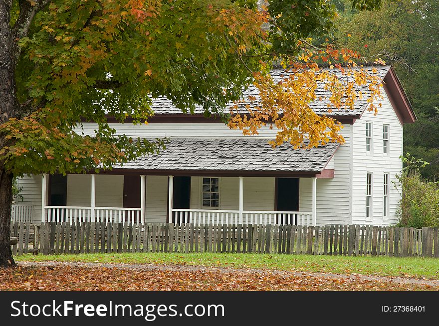 An antique white house in fall.