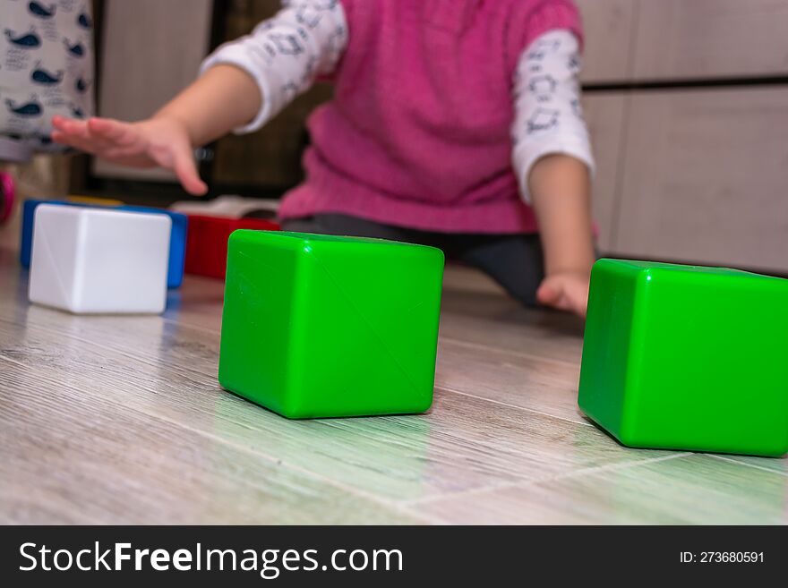Child playing with colorful cubes on the floor in the living room