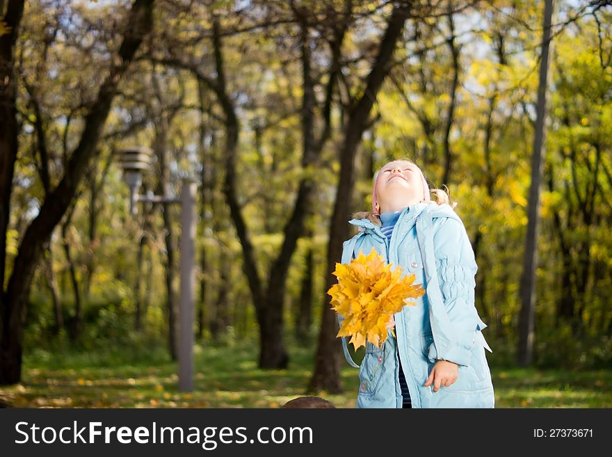 Young Girl Holding Fallen Leaves and Looking up