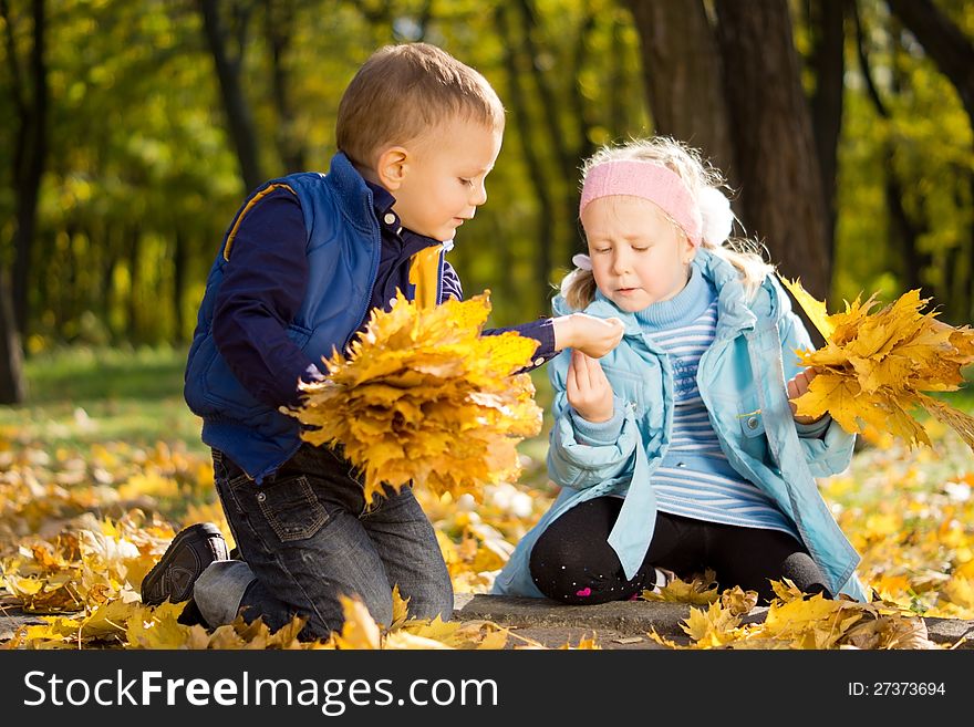 Young Children Gathering Leaves In Autumn Splendor