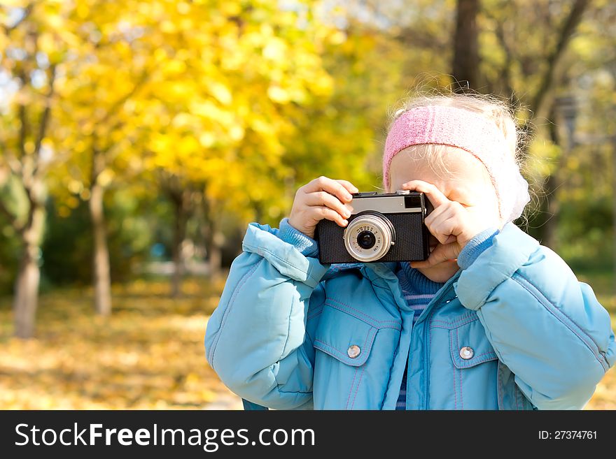 Small girl standing in autumn woodland taking a photograph using a vintage slr camera. Small girl standing in autumn woodland taking a photograph using a vintage slr camera