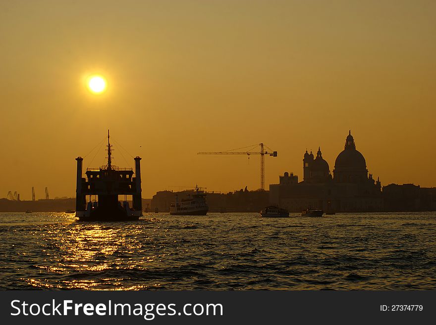Sunset in the Lagoon in Venice in Italy with silhouettes of ships and Basilica of Santa Maria della Salute. Sunset in the Lagoon in Venice in Italy with silhouettes of ships and Basilica of Santa Maria della Salute