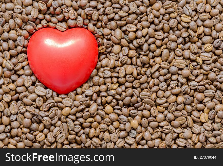 Detailed roasted coffee beans background with red heart symbol on it. Detailed roasted coffee beans background with red heart symbol on it