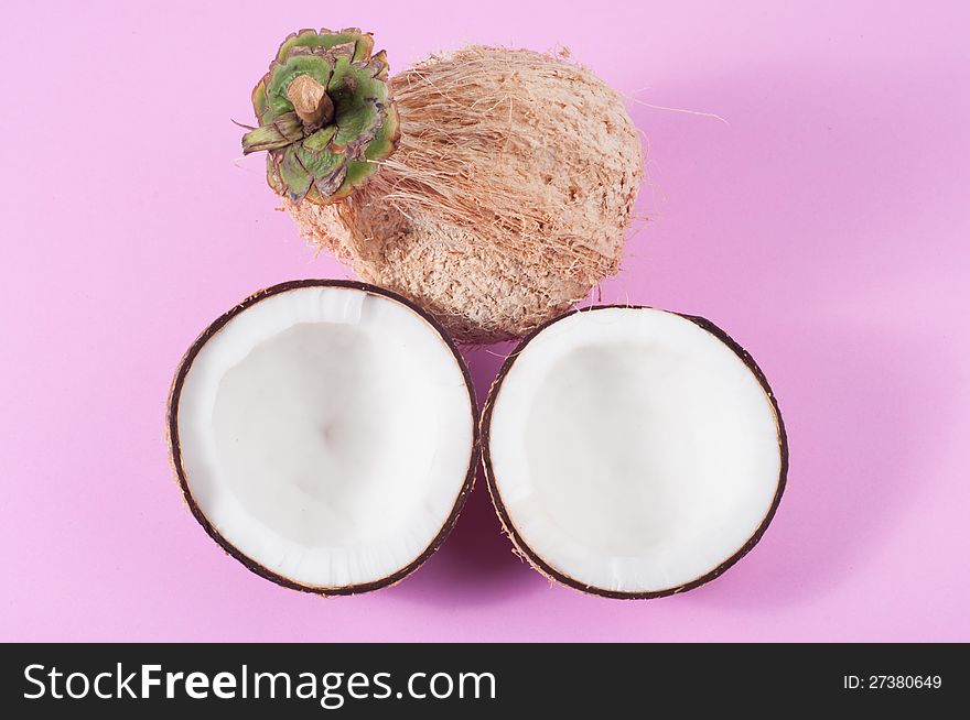 Two halfs of coconut  on pink background with shadow. Two halfs of coconut  on pink background with shadow