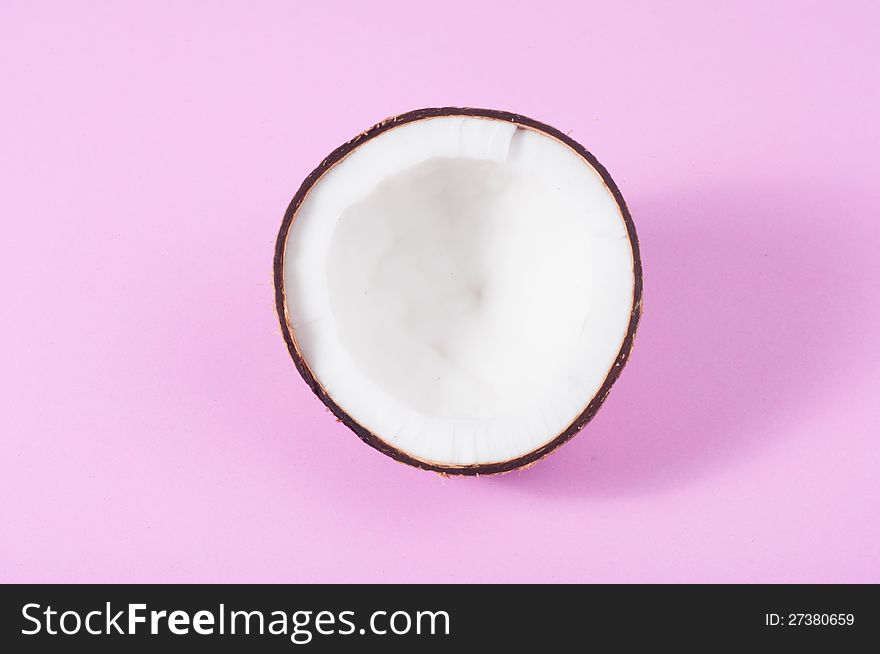 Halfs of coconut on pink background with shadow