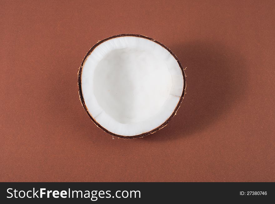 Halfs of coconut on brown background with shadow. Halfs of coconut on brown background with shadow