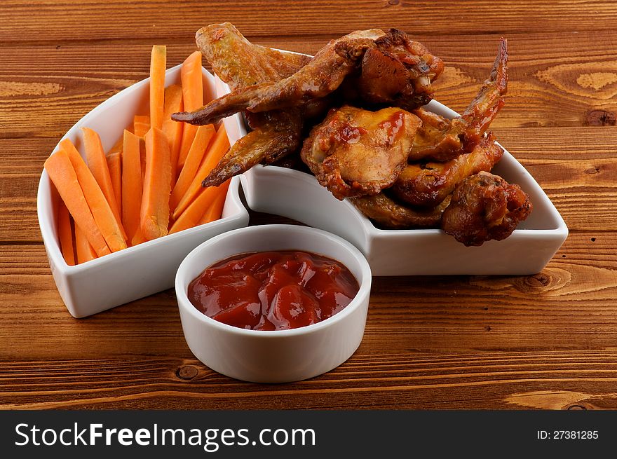 Chicken Wings, Carrot Sticks and Barbecue Dressing in White Bowls on Wood background