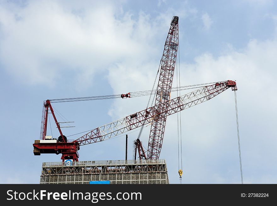 Construction cranes over blue sky.