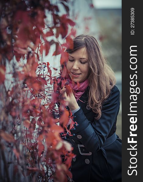 Girl looks at the red leaves smiling. Girl looks at the red leaves smiling